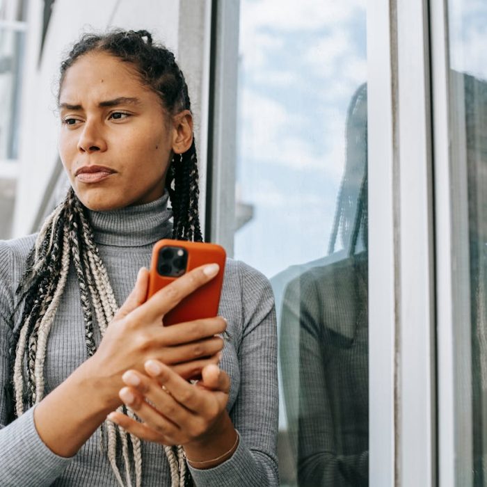 Mulher em reflexão com smartphone representando violência psicológica contra a mulher e busca por informação e proteção legal
